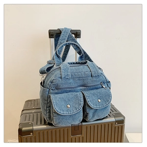 Detail of vintage denim crossbody bag with dual pockets on a silver suitcase