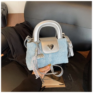 Macro shot of silver heart-shaped metal buckle on light blue denim texture handbag