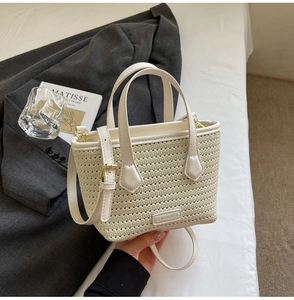 Detail of hand-woven white bucket bag with PU handles and metallic solar and miss plaque