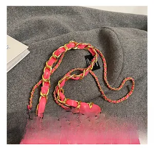 Detail of fuchsia quilted leather texture with gold metal chain strap on a woven background