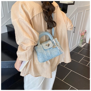 Close-up of light blue pleated handbag with heart-shaped metal clasp and shoulder strap