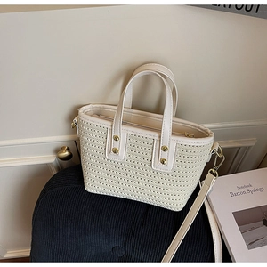 Detail of cream woven bucket bag with gold rivets and smooth synthetic leather handle