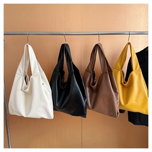 Detailed row of large tote bags in white, black, brown and yellow on metal hangers