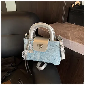 Detail of blue denim mini bag with silver mirror leather handle and heart buckle