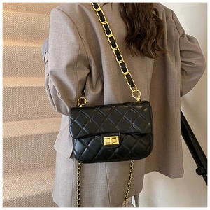 Detail of black quilted chain bag with gold metal buckle worn with a grey blazer