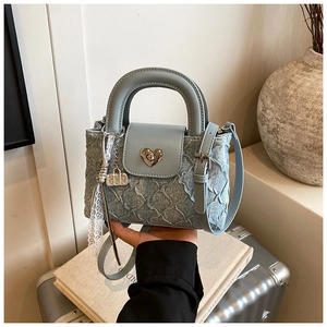 Detail of light blue denim handbag featuring diamond quilting and heart-shaped metal lock