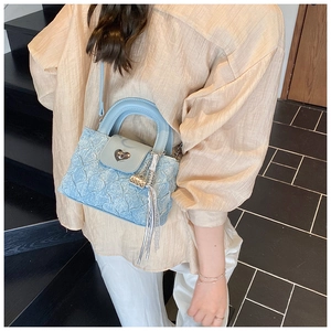 Detailed view of light blue pleated handbag with silver heart lock and tassel charm