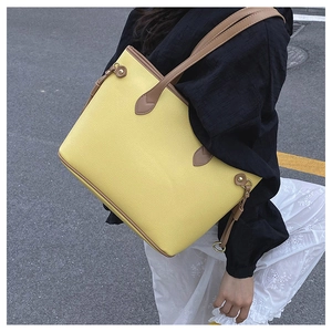 Detail of yellow pebbled leather tote bag with brown straps and gold rivet accents