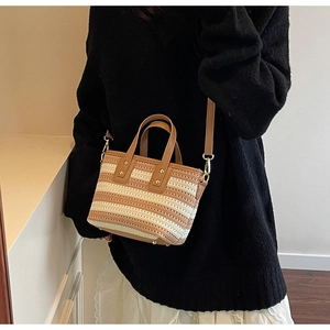 Close-up of hand-woven bucket bag with brown leather handle and gold hardware detail
