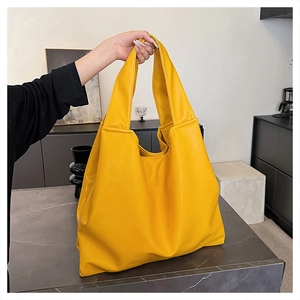 Detail of soft yellow PU leather tote bag with fine texture on black marble surface