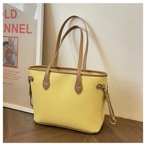 Detail of lemon yellow tote bag with pebble leather texture and brown edge piping