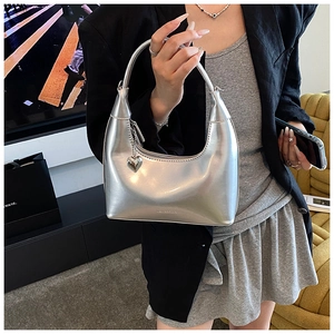 Detail of silver mirror crescent bag with heart pendant and embossed brand logo on base