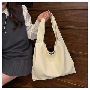 Macro detail of creamy white PU leather tote bag with wide shoulder strap on wooden stairs