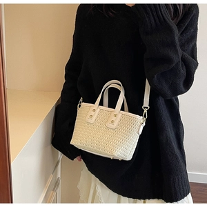 Detail of hand-woven cream bucket bag featuring fine texture and gold metal hardware