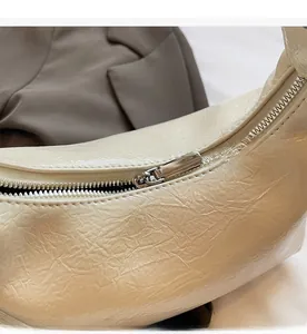 Gros plan sur la fermeture éclair lisse et la texture plissée du sac à main beige