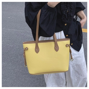 Detail of yellow lychee grain leather tote bag with brown straps and golden metal buckle