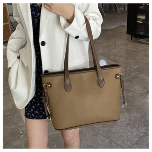 Detailed view of brown tote bag with litchi texture and gold metal ring accent