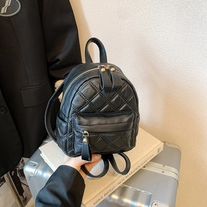 Mini black quilted PU leather backpack with gold hardware in a fashion travel setting