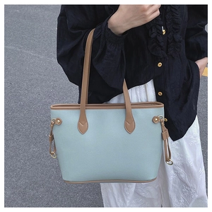 Detailed shot of large mint blue tote bag with brown leather handles on shoulder