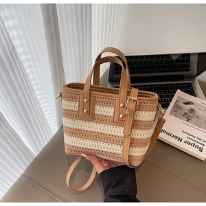 Detail of woven bucket bag featuring brown stripes, leather strap and gold hardware