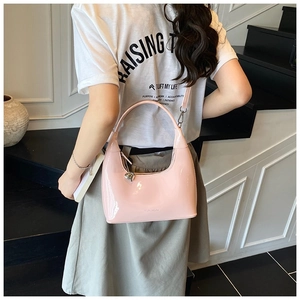 Detail of pink patent leather hobo bag with glossy finish and silver heart charm