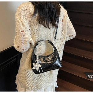 Detail of black wrinkled patent leather hobo bag with silver star charm and strap