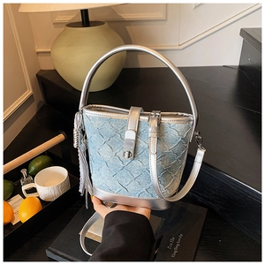 Gros plan du sac seau en denim bleu clair avec texture matelassée et bordure argentée