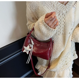 Detail of red patent leather dumpling bag with silver star pendant and tassel decoration