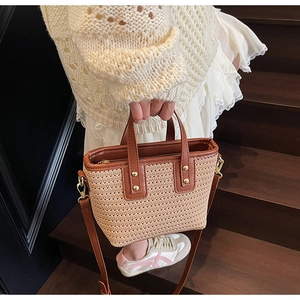 Detail of woven bucket bag with brown leather handles and gold metal studs decoration