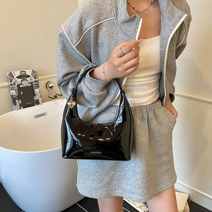 Glossy black patent leather crescent hobo bag with heart pendant shown as underarm style
