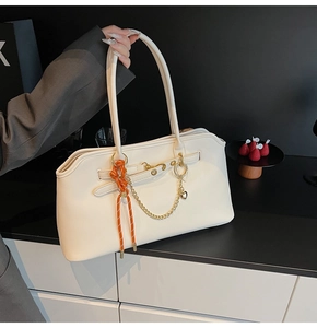 Dettaglio borsa tote in pelle bianca con catena in metallo e cordino intrecciato arancio