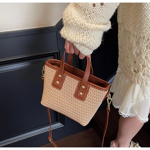 Detail of hand-woven bucket bag featuring brown leather trim and gold rivet accents