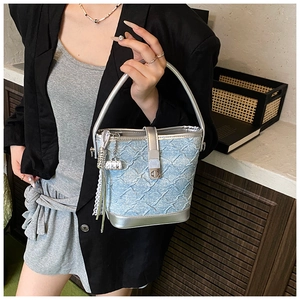 Détail du sac seau en jean bleu clair avec bordures en cuir argenté et ruban dentelle