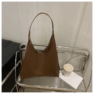 Detail of soft dark brown leather tote bag with long slim shoulder strap on silver shelf