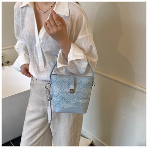 Détail du sac seau bleu clair avec motif à losanges et charm en dentelle