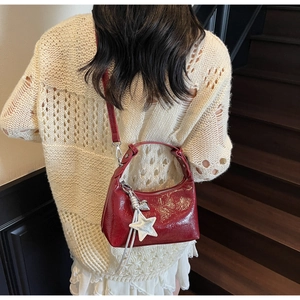Detail view of burgundy patent leather bag with a large silver star pendant accessory