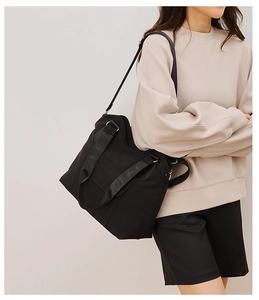 Close-up of a black canvas tote bag showing dual handles and a versatile shoulder strap