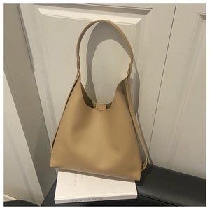 Close-up of khaki faux leather tote bag on white books with minimalist hobo design