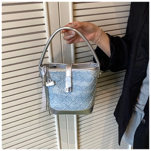 Détail du sac seau bleu clair avec texture plissée et poignées métalliques argentées