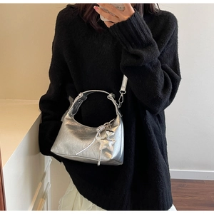 Detail of silver metallic hobo bag with star and heart charms worn by a model
