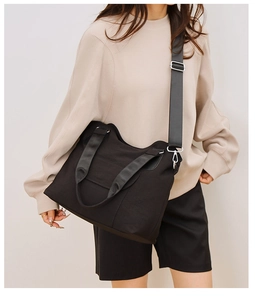 Close-up of black canvas tote bag with adjustable strap and silver metal hooks