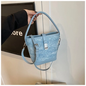 Détail du sac seau bleu clair avec texture denim, boucles argentées et bandoulière