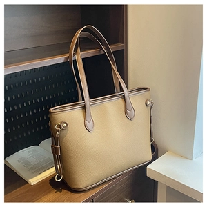 Detail of khaki pebbled leather tote bag with vintage rivets on dark wooden background