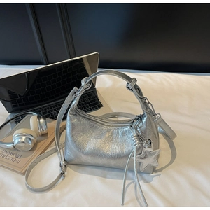 Detail of silver metallic wrinkled crescent bag with star pendant and sleek tassel