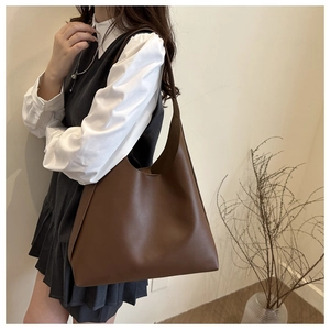 Side view of large brown faux leather tote bag worn by model for daily commute style