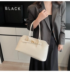 Dettaglio della borsa a tracolla crema con chiusura dorata su un outfit blazer grigio