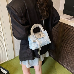Blue denim crossbody bag with silver heart lock and pleated texture shown on model