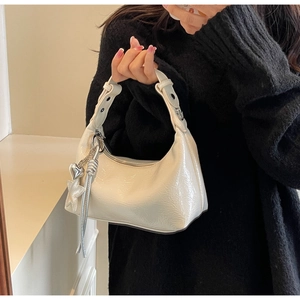 Detail of white patent leather hobo bag with silver heart and star charms on strap