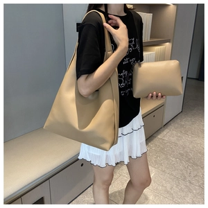 Detailed view of khaki leather tote bag and pouch set on a fashion model