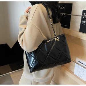 Borsa tote trapuntata nera con catena in metallo vista da un'angolazione di 45 gradi